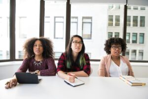 A team of 3 women sit around a table asking tough questions to overcome employee relations issues.