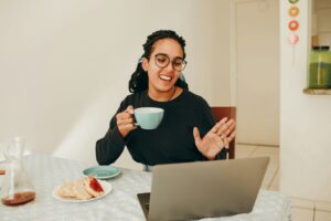Woman completing Virtual Onboarding on a laptop at home while eating breakfast.