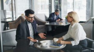 Business man and business women talking over cups of coffee.